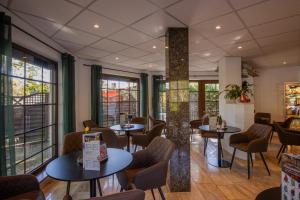 ein Restaurant mit Tischen, Stühlen und Fenstern in der Unterkunft Ferien Hotel Cottbus in Kolkwitz