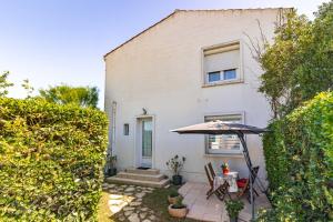 a house with an umbrella and a table and chairs at Appartement À Saint-Pierre-d'Oléron in Saint-Pierre-dʼOléron