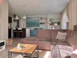 a living room with a brown couch and a table at Luxe Duinsuite in Groet