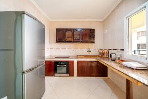 a kitchen with wooden cabinets and a refrigerator at First Line Beach & Free Parking in Tangier