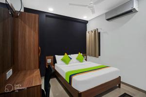 a bedroom with a bed with green pillows at Hotel Wow in Surat