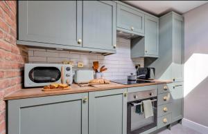 a kitchen with blue cabinets and a microwave at Ivydene Cottage Hawsker in Whitby