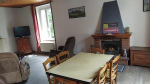 a living room with a table and a fireplace at Location maison in Neussargues-Moissac