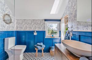 a blue bathroom with a tub and a toilet at Ivydene Cottage Hawsker in Whitby +14 photos