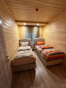 two beds in a room with wooden walls at Nirvana Suite Hotel in Uzungöl