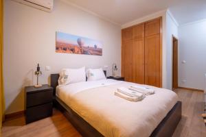 a bedroom with a bed with towels on it at FamilyHub - EcoHost - Spacious 3-bedroom apartment for 8 people with AC and parking near Porto and the beaches in Senhora da Hora