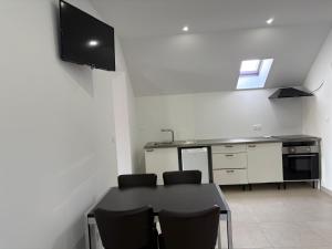 a kitchen with a table and a tv on a wall at Hôtel-Restaurant Belle'man in Longevelle-sur-Doubs