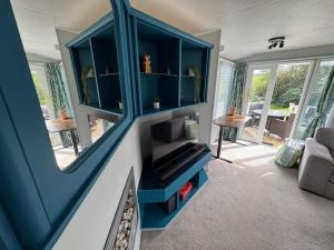 a living room with a fireplace and a blue cabinet at Bag End, Near Porth Beach, Garden & Stream in Newquay Bay Resort