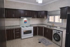 a kitchen with wooden cabinets and a white stove top oven at Spacious Apartment in Amman