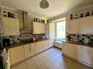 a large kitchen with white cabinets and a window at McCaig's Tower Apartment in Oban