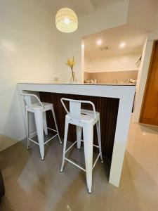 a kitchen with two white stools and a counter at Casa Serenity Transient House in General Trias