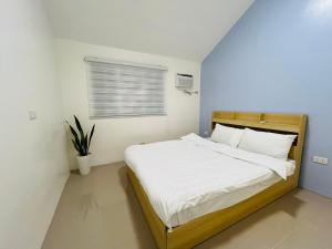 a bedroom with a bed with white sheets and a window at Casa Serenity Transient House in General Trias