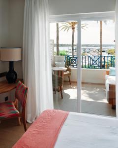a bedroom with a bed and a view of a balcony at Hotel Honucai in Colònia de Sant Jordi