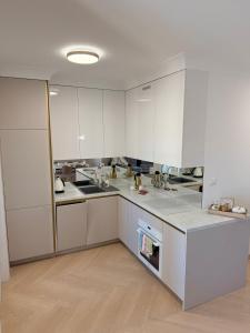 a white kitchen with white cabinets and a wooden floor at Olimpia Luxury Apartment in Lębork