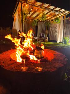 a fire pit with wine glasses in front of it at Vale Infinito Chalé in Córrego do Bom Jesus