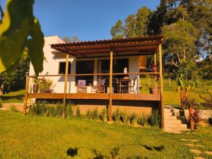 a woman sitting on the deck of a house at Vale Infinito Chalé in Córrego do Bom Jesus