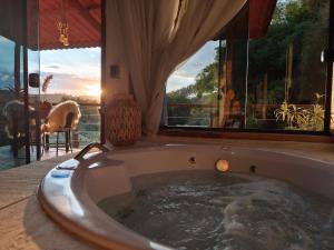 a jacuzzi tub in a room with a window at Vale Infinito Chalé in Córrego do Bom Jesus +75 photos