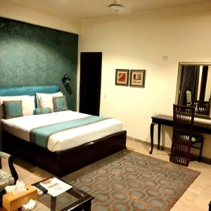 a bedroom with a bed and a desk in it at Shelton Hotel Johar Town Lahore in Lahore
