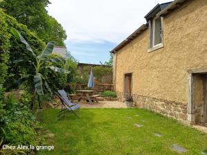 a garden with a table and a chair and an umbrella at Chez Alex, La Grange in Saint-Brieuc-des-Iffs