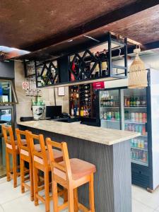 a bar with four chairs and a counter with drinks at Solovina Guest House in Foso