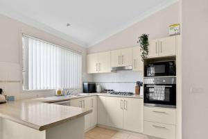 a large white kitchen with white cabinets and appliances at Serena Shores Holiday Escape in St Georges Basin