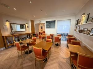 a restaurant with wooden tables and chairs and a chalkboard at Americana Hotel in London
