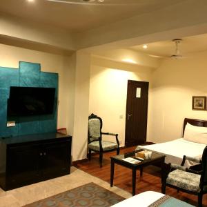 a living room with a bed and a tv at Shelton Hotel Johar Town Lahore in Lahore +34 photos