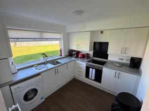 a kitchen with white cabinets and a sink and a dishwasher at Chapelhall Contractor Stay in Chapelhall +21 photos