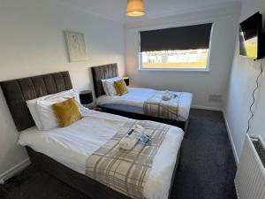 a bedroom with two beds and a window at Chapelhall Contractor Stay in Chapelhall