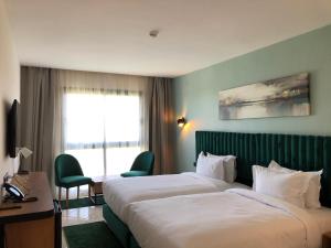 a hotel room with two beds and a window at Hôtel Hariz Son in Berrechid