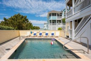 a swimming pool with chairs and a house at Heron Landing in Corolla