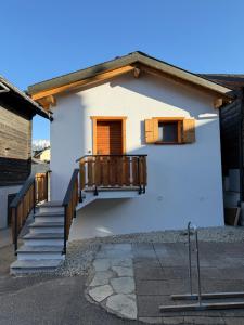 a small white house with a wooden porch and stairs at Le mazot in Lens
