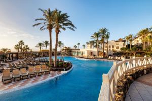 a pool at a resort with chairs and palm trees at Occidental Jandía Mar - All Inclusive in Morro del Jable