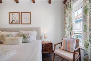 a bedroom with a bed and a chair and a window at Flor de Sol House in Tavira