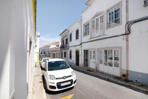 a white car parked on the side of a street at Flor de Sol House in Tavira