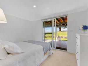a white bedroom with a bed and a sliding glass door at Elysian Shores in Long Beach