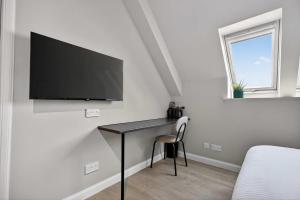 a bedroom with a desk with a tv on a wall at Sanctuary Hotel - En Suite Rooms in Aberdeen