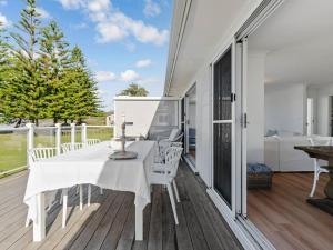 a white dining room with a white table and chairs on a deck at Elysian Shores in Long Beach