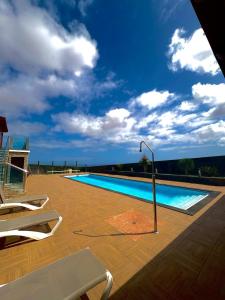 a swimming pool with chairs and a light pole next to it at Villa en el Time con piscina in Puerto del Rosario