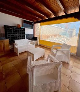 a living room with white chairs and a patio at Villa en el Time con piscina in Puerto del Rosario