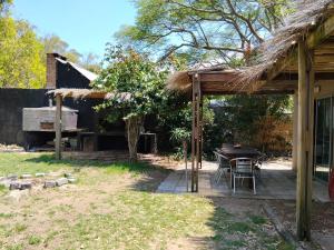 a patio with a table and a thatch roof at Bosque del Este in Balneario Buenos Aires
