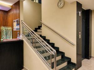 a staircase in a building with a clock on the wall at Hotel Konark Inn in Indore
