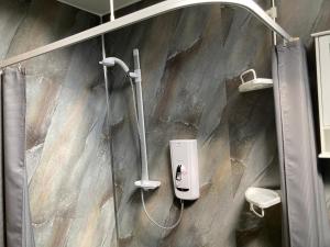 a shower in a bathroom with a stone wall at Jakels Rest in Lairg +9 photos
