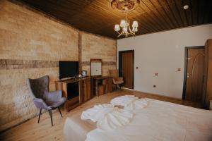 a bedroom with a bed with a chair and a television at Konak Stone House in Ürgüp +62 photos