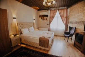 a bedroom with a bed and a chair and a television at Konak Stone House in Ürgüp
