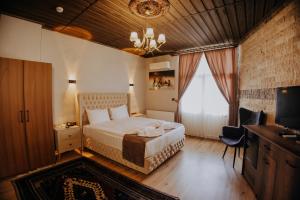 a bedroom with a bed and a desk and a television at Konak Stone House in Ürgüp