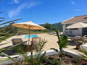 a patio with an umbrella and chairs and a pool at Hacienda Gallego in Málaga