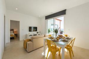 a living room with a table and a couch at Villa Las Palmeras Valdevaqueros Suites, Pool & Sea Views in Tarifa