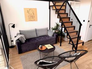 a living room with a couch and a spiral staircase at Wczasowy Loft Sominy in Sominy