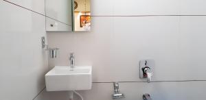 a white bathroom with a sink and a mirror at Nova Yashraj Hotel in Rajkot +25 photos